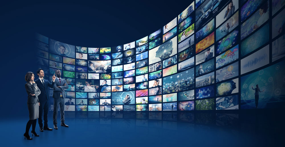 People in suits looking at a wall of screens