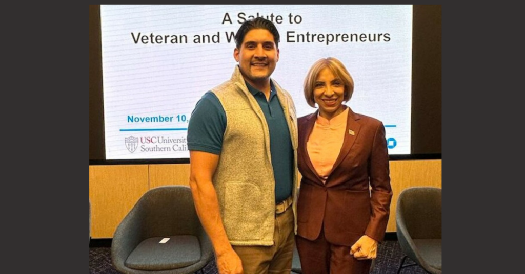 Eric Vasquez at veteran event standing with attendee smiling