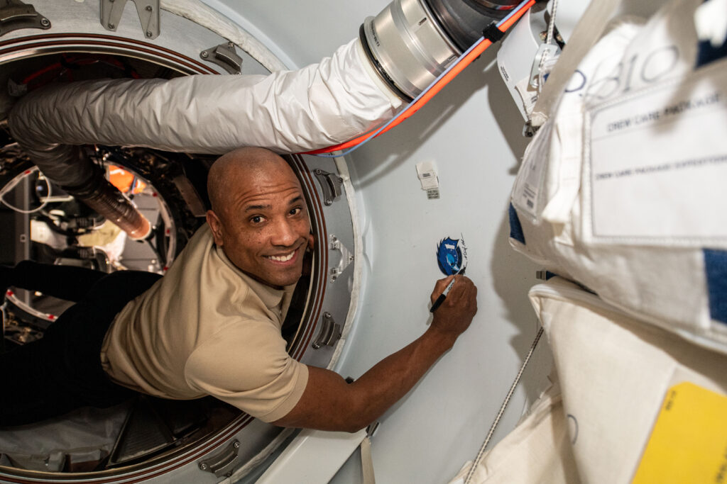 SpaceX Crew-1 pilot Victor Glover Jr. of NASA signs his name on the international docking adapter