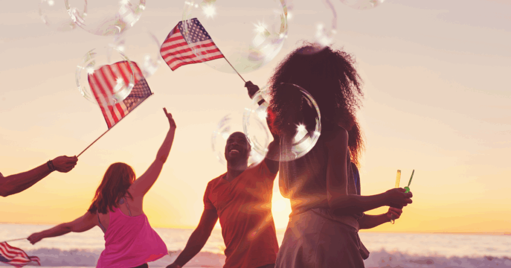 group celebrating the 4th of July waving flags at the beach