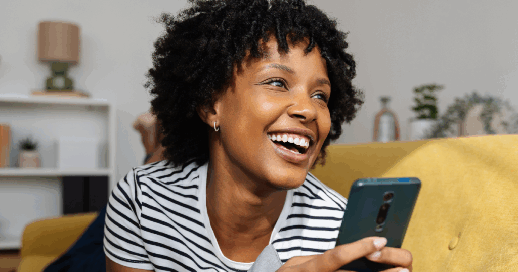 woman smiling at some news from a smartphone
