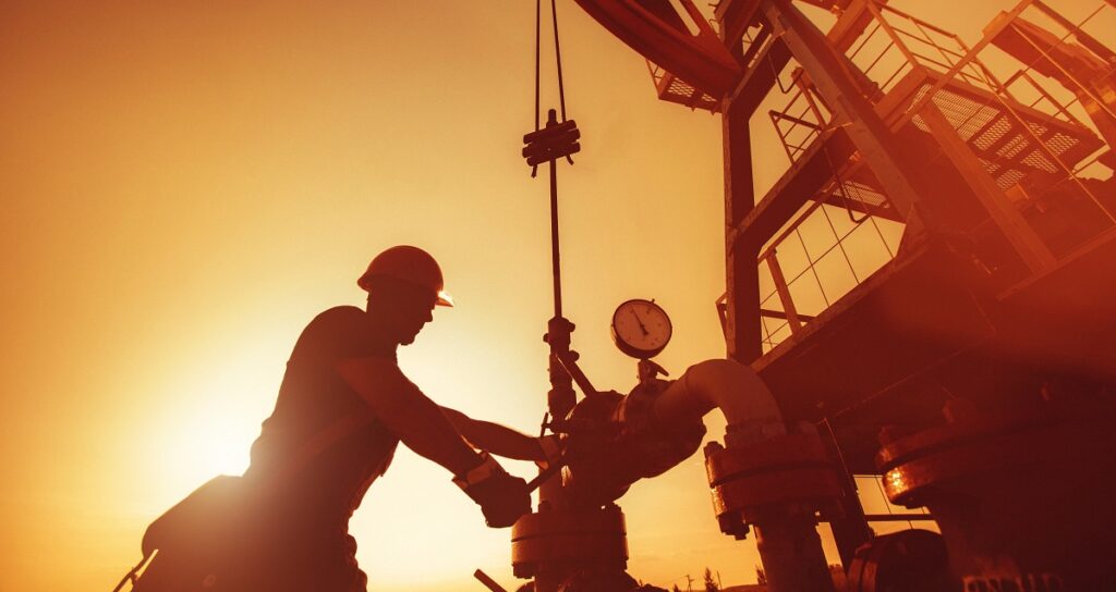 Energy Evolution: How Oil & Gas Workers Can Lead the Shift Oil worker is checking the oil pump on the sunset background.