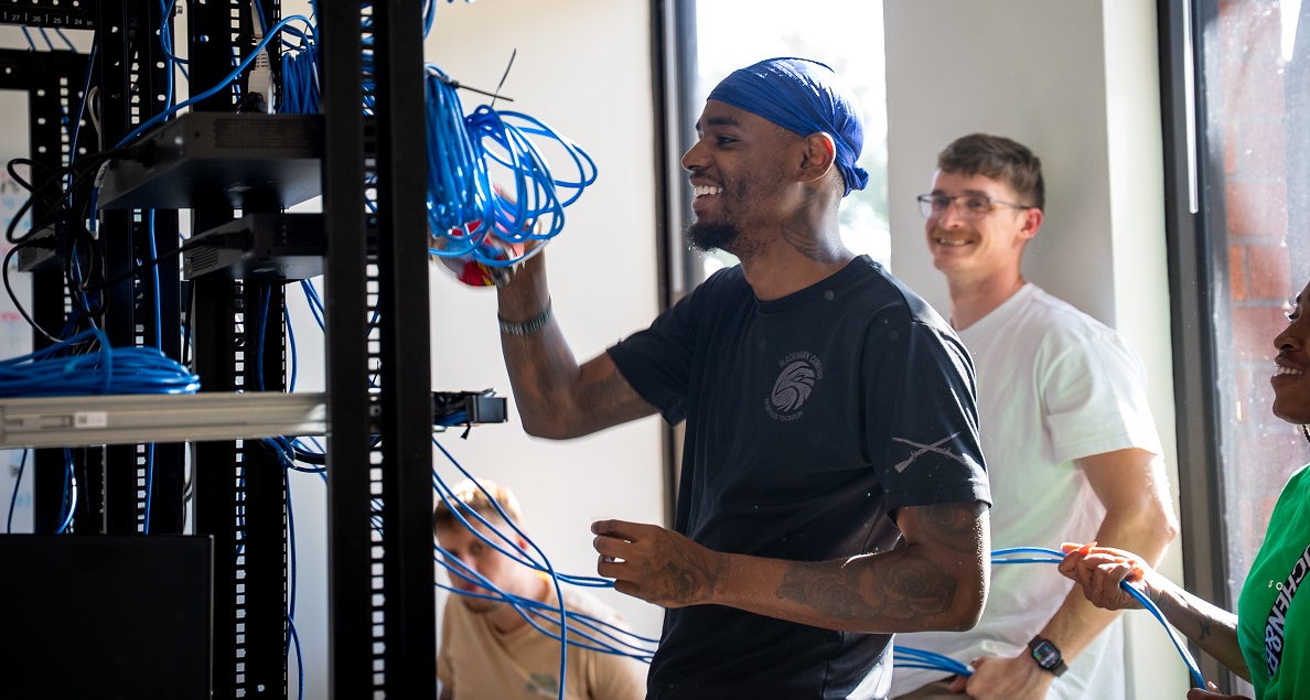 man working on electrical unit with students looking on