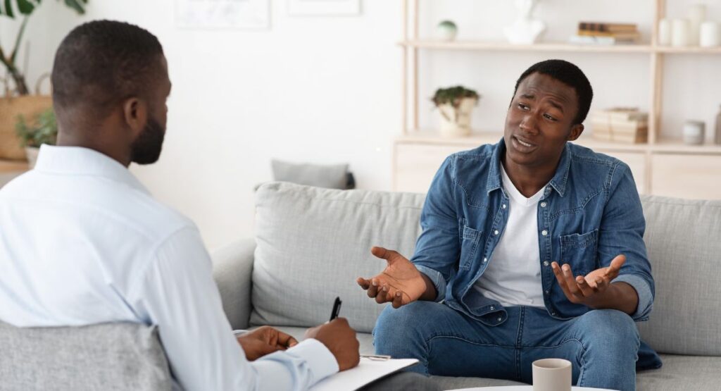 PTSD (Self) Awareness: A New Year’s Reflection Begins in the Mirror man speaking with therapist in an office setting